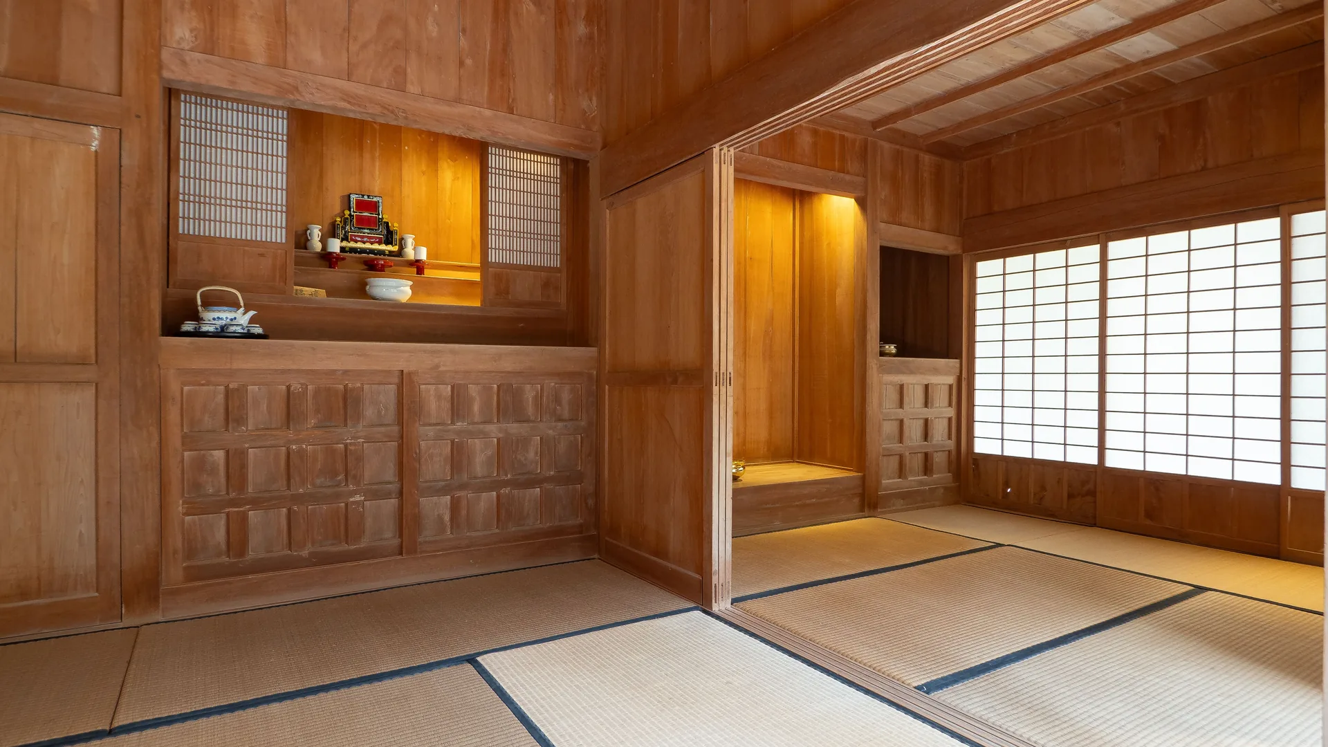 Tradiční japonská místnost s tmavým dřevěným obložením, podlahami z tatami a papírovými posuvnými stěnami šódži